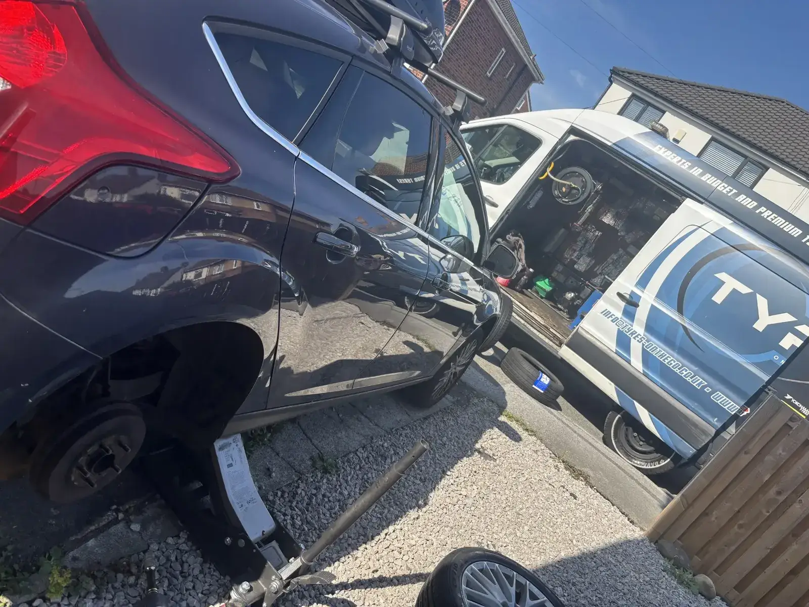Mobile tyre fitter working on a car at a customer's home in West Yorkshire